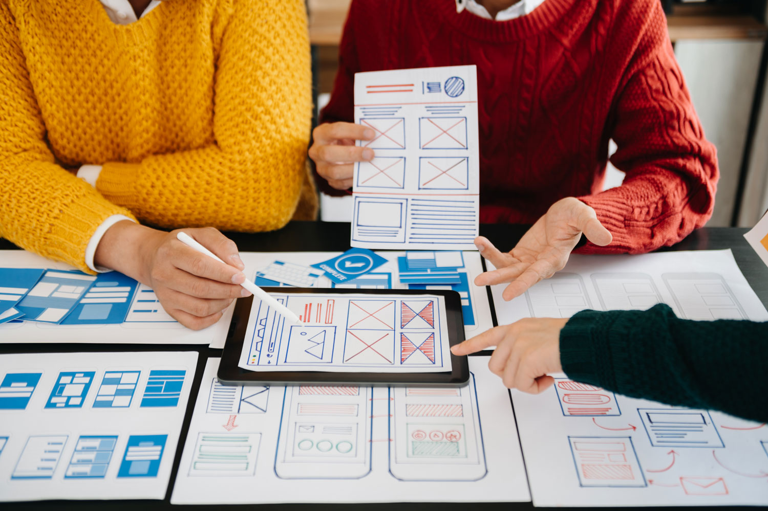 Group of people sitting around table looking at different layouts of a design - responsive web design agency
